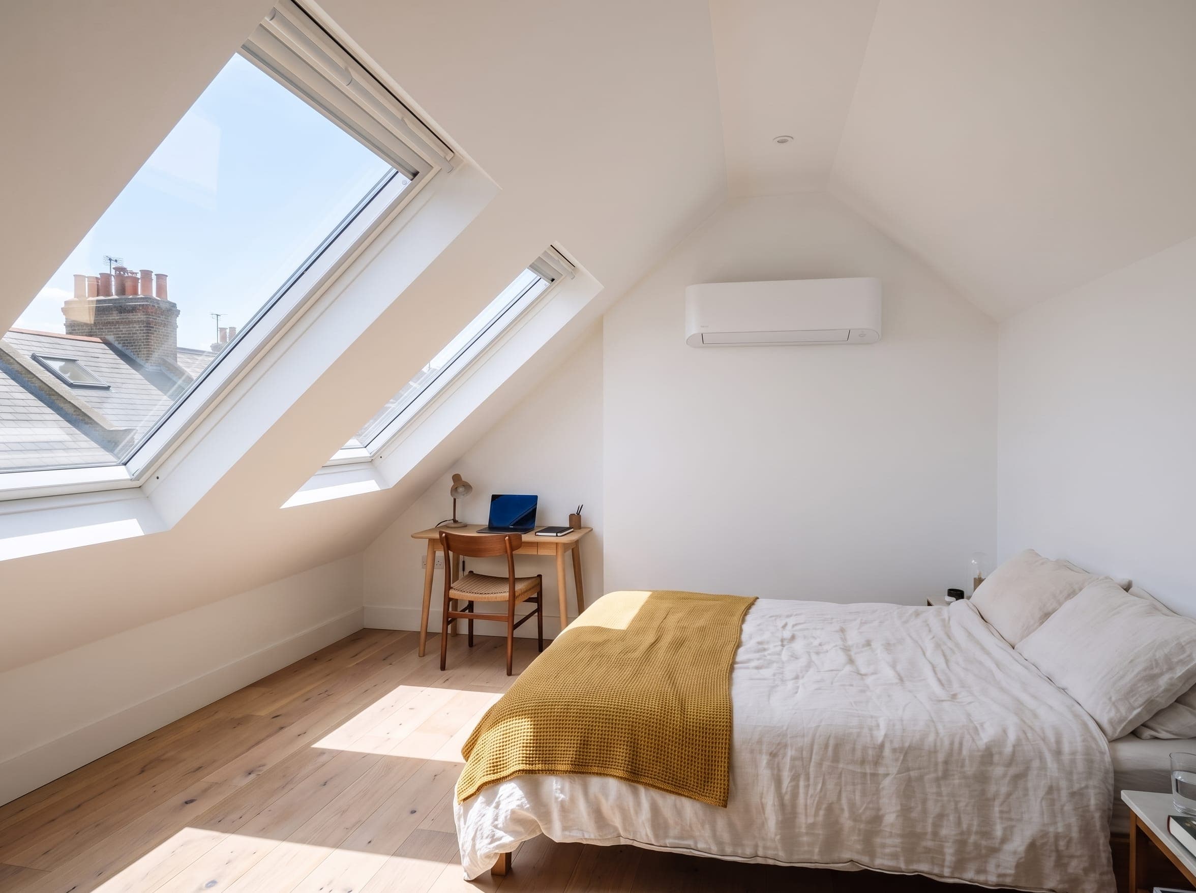 Loft conversion bedroom with roof windows and an air conditioning unit on the gable wall