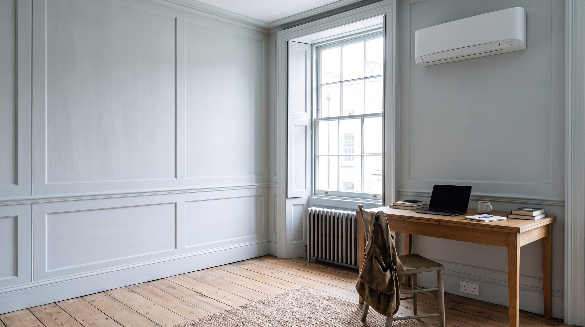 Sleek matte wall-mounted air conditioning unit above a desk in a Georgian townhouse study