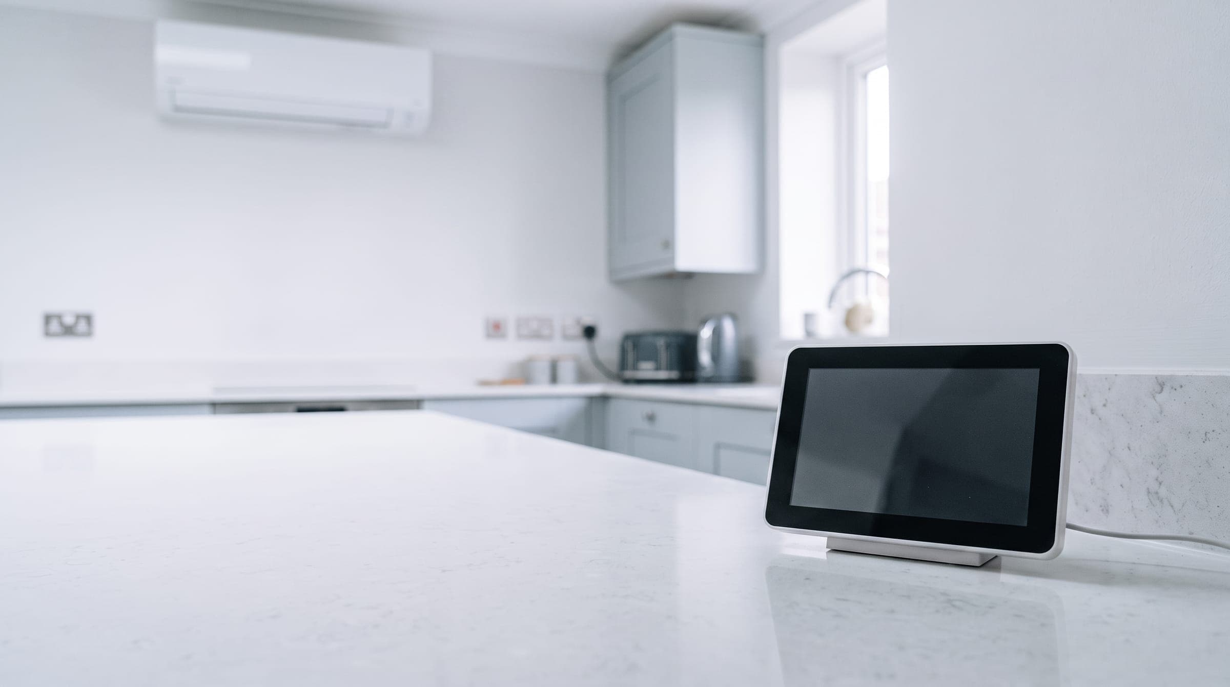 Smart energy meter display with a blank screen on a kitchen worktop, with a white wall unit softly out of focus behind