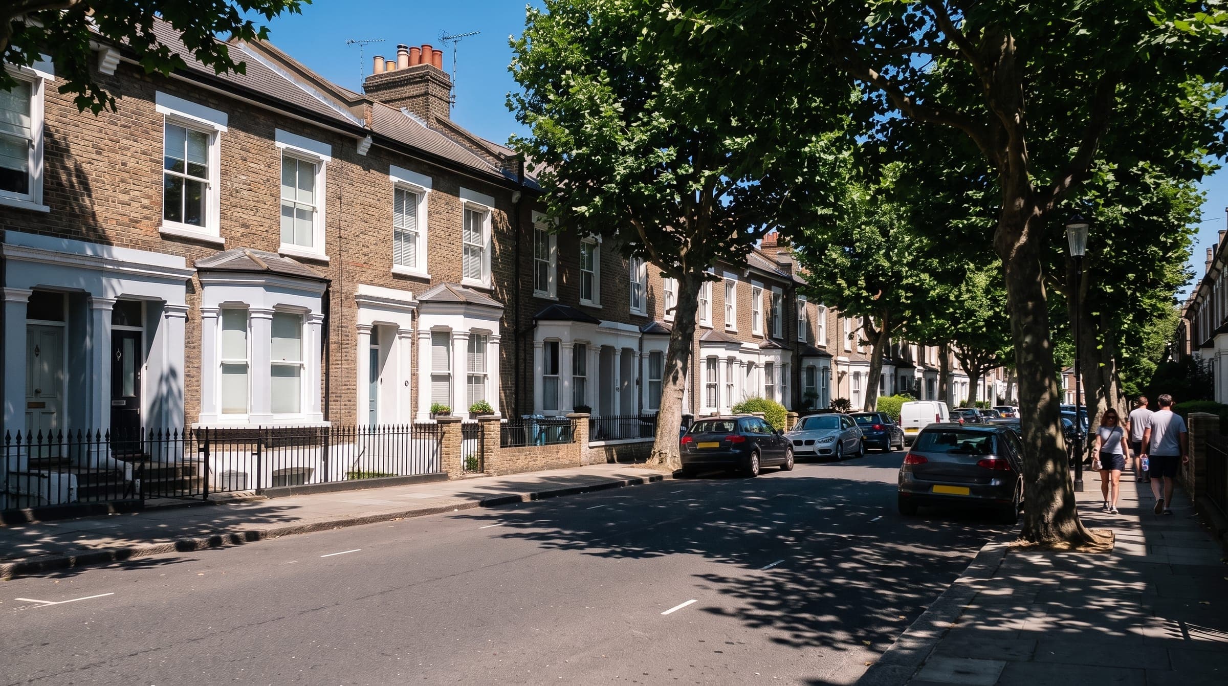 Sunny London street of terraced houses in a summer heatwave, with people keeping to the shade under the trees