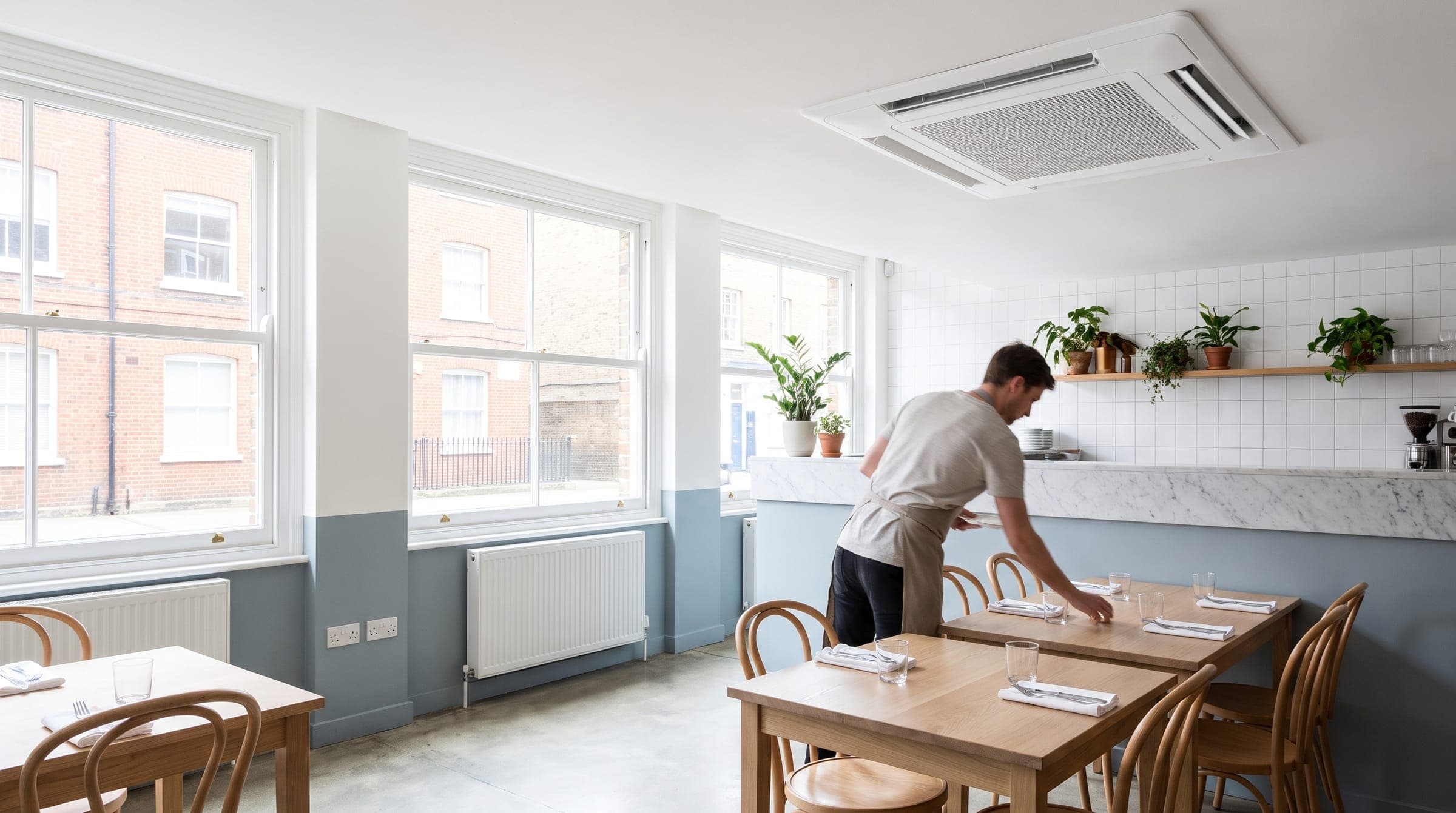 Bright neighbourhood restaurant with a ceiling cassette air conditioning unit above the tables